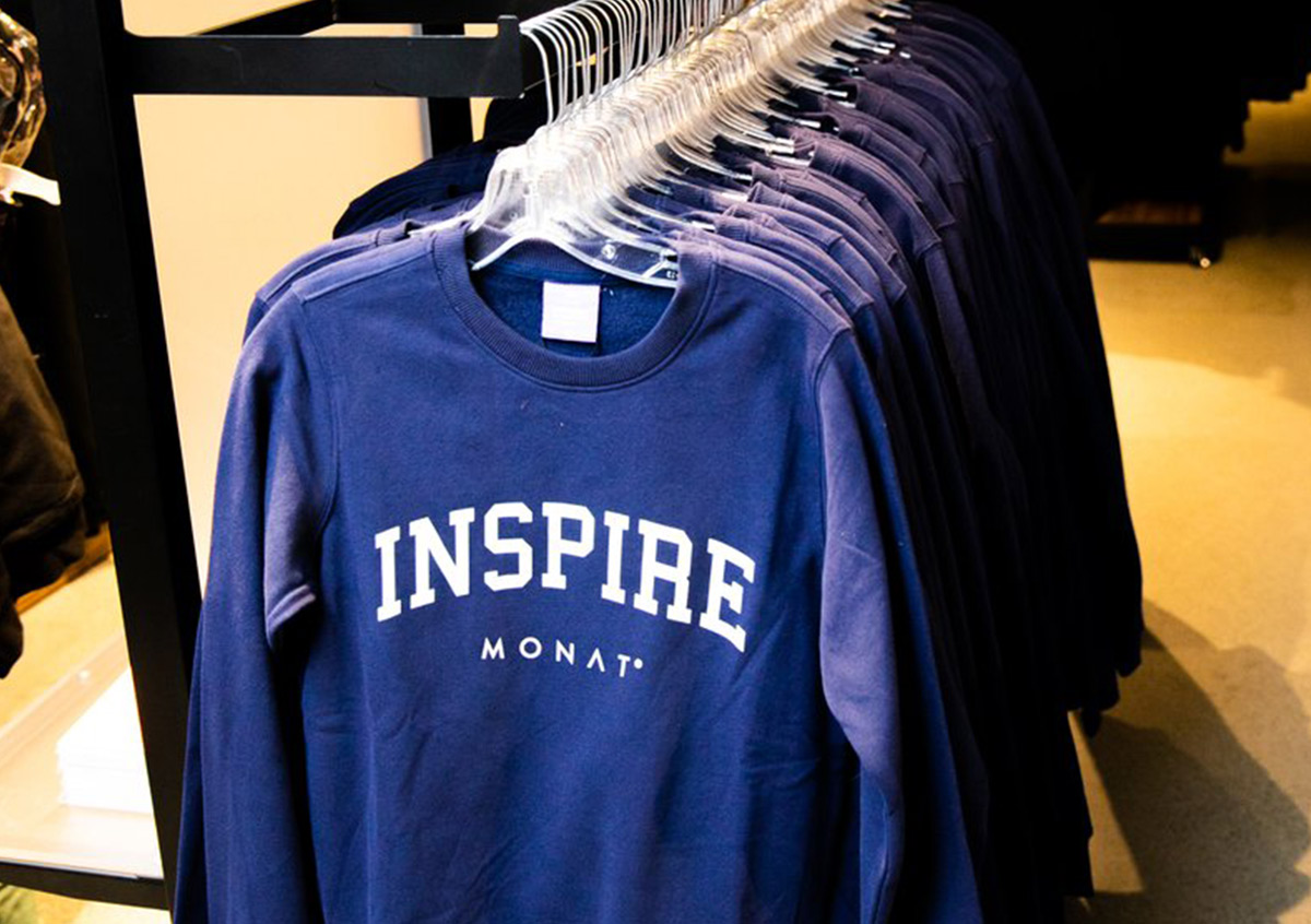 Navy blue sweatshirts that say INSPIRE MONAT, available at the MONAT Gear store at the MONATions expo.