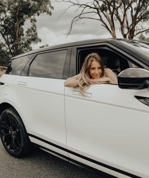 Brunette woman holding Car keys standing in front of a white car