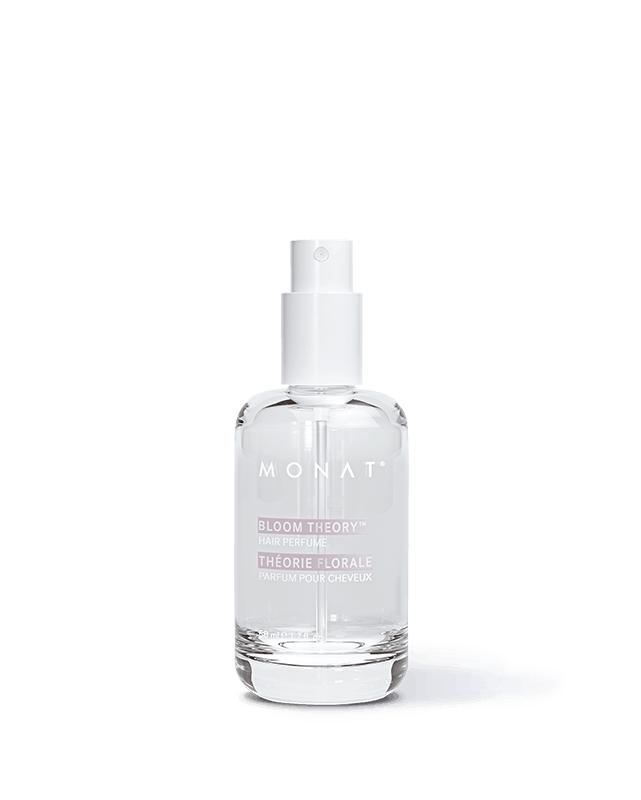 Clear glass spray bottle of MONAT Bloom Theory hair perfume with white cap, on a white background and soft shadow