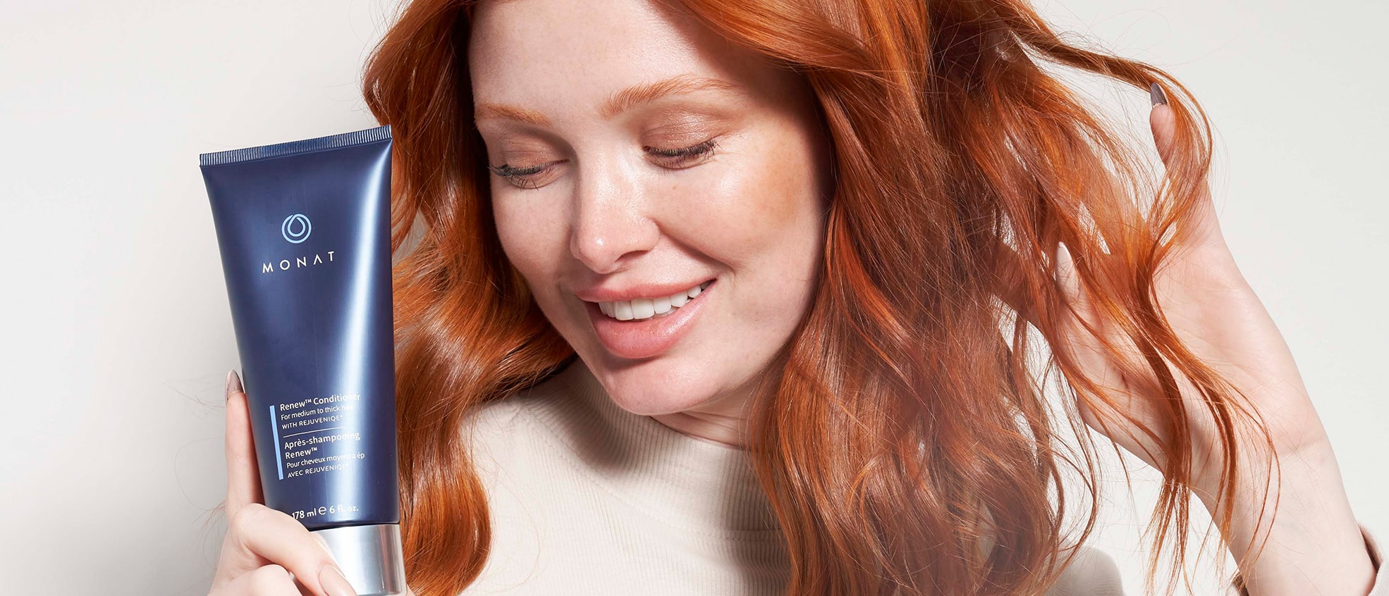 Red-haired woman holding a tube of Renew Conditioner.