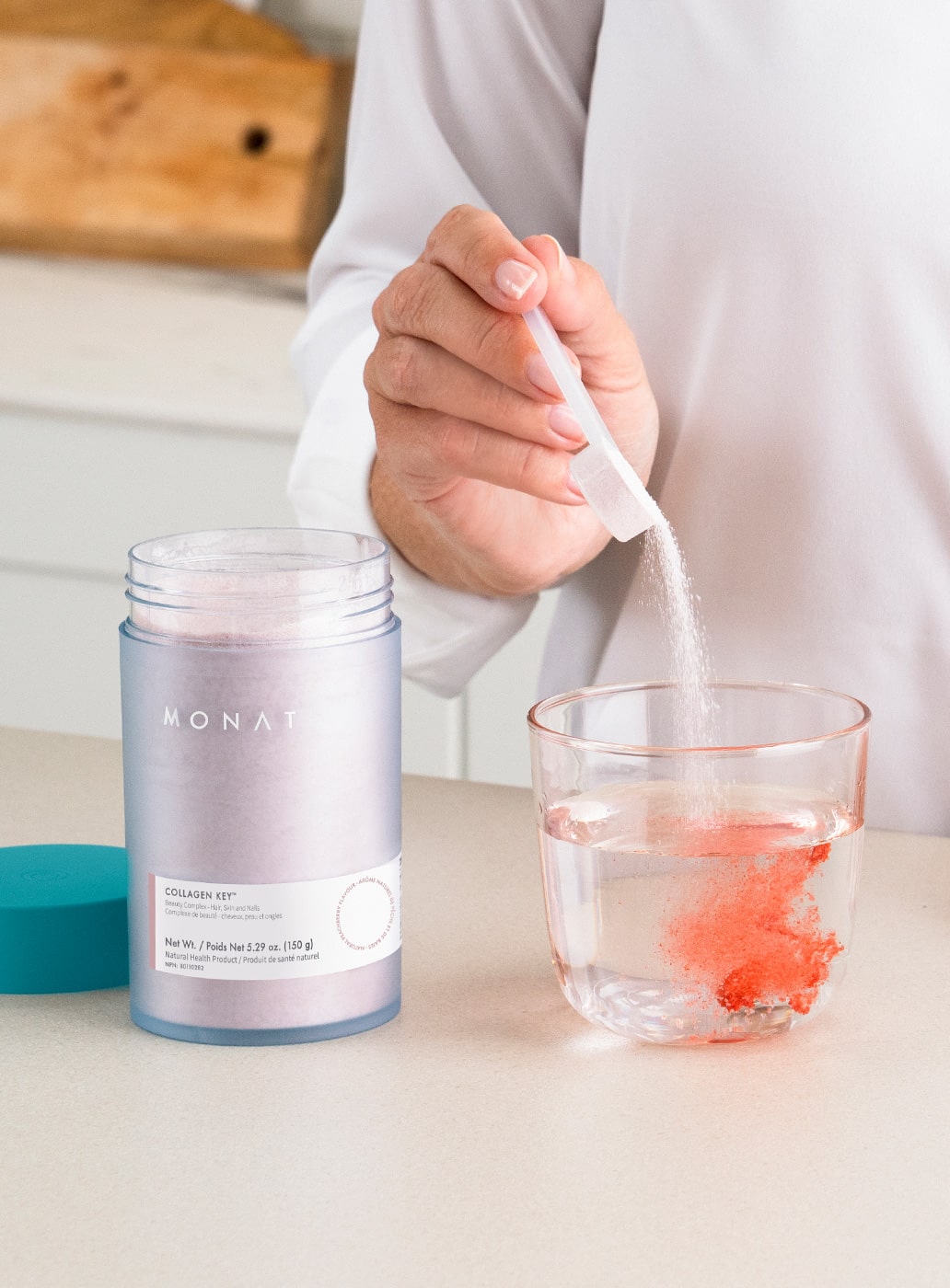 A woman stirring a drink of MONAT COLLAGEN KEY with a spoon