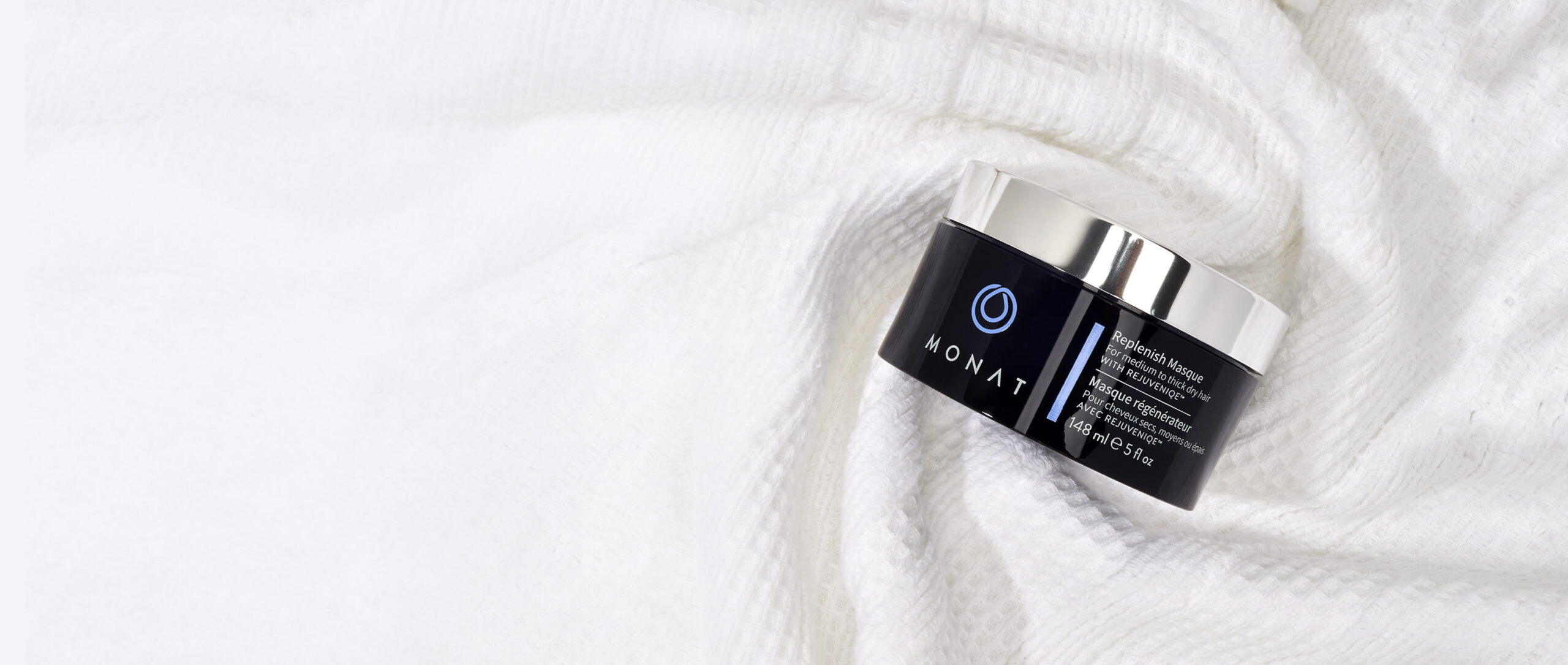 MONAT Replenish Masque jar resting on a soft white towel.