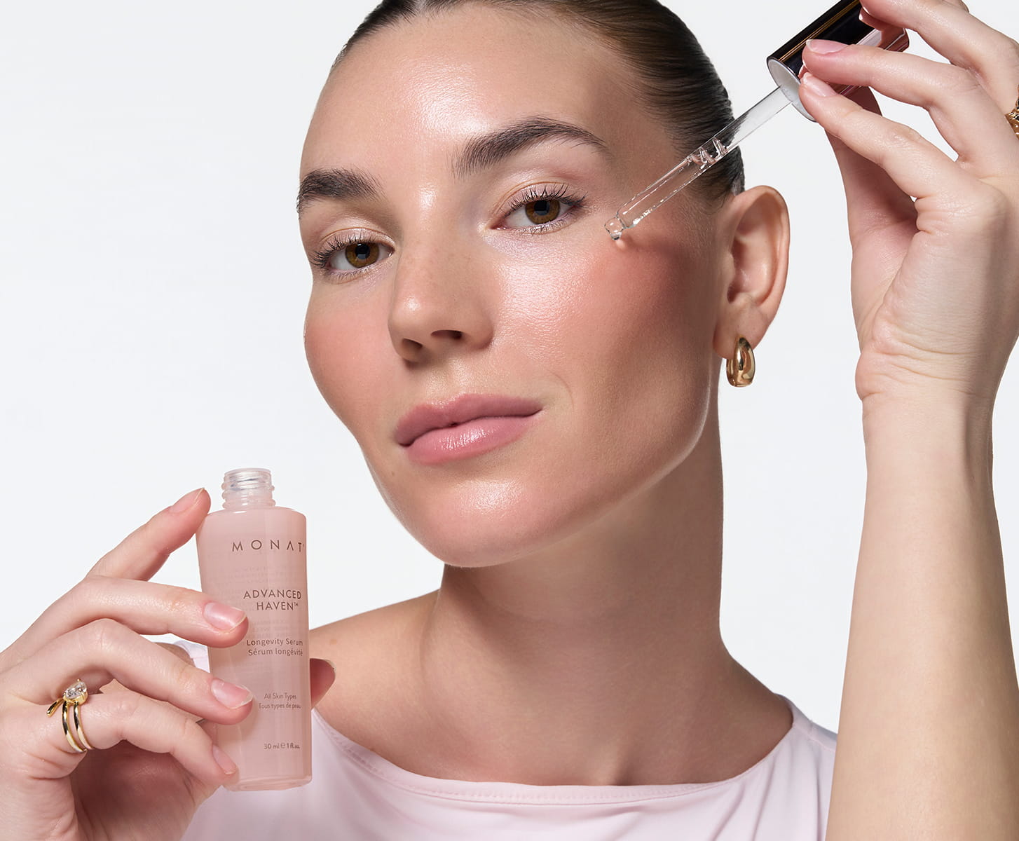 Smiling woman holding MONAT Barrier Booster™ Barrier Defense Moisturizer jar near her cheek.