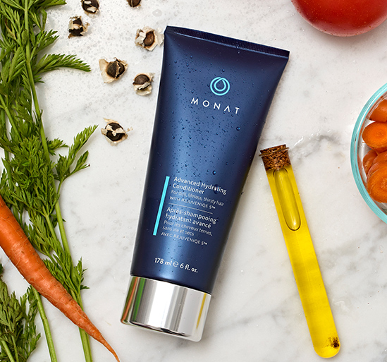 Advanced Hydrating Conditioner laying on a flat surface, along with ingredients such as carrots, tomatoes and oil.