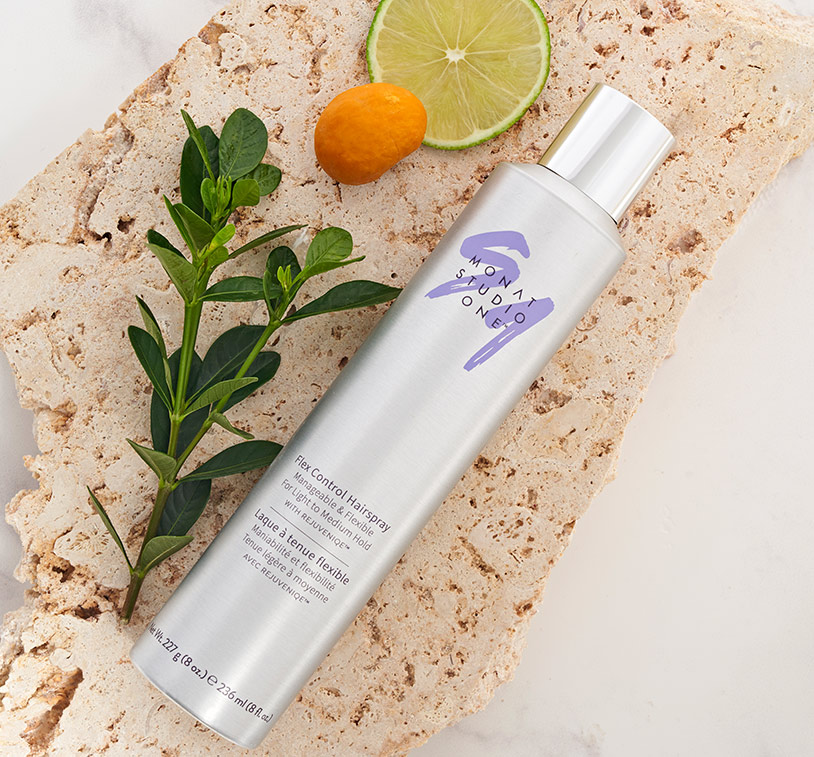 MONAT STUDIO ONE™ Flex Control Hairspray laying on a stone, next to greenery and ingredients.