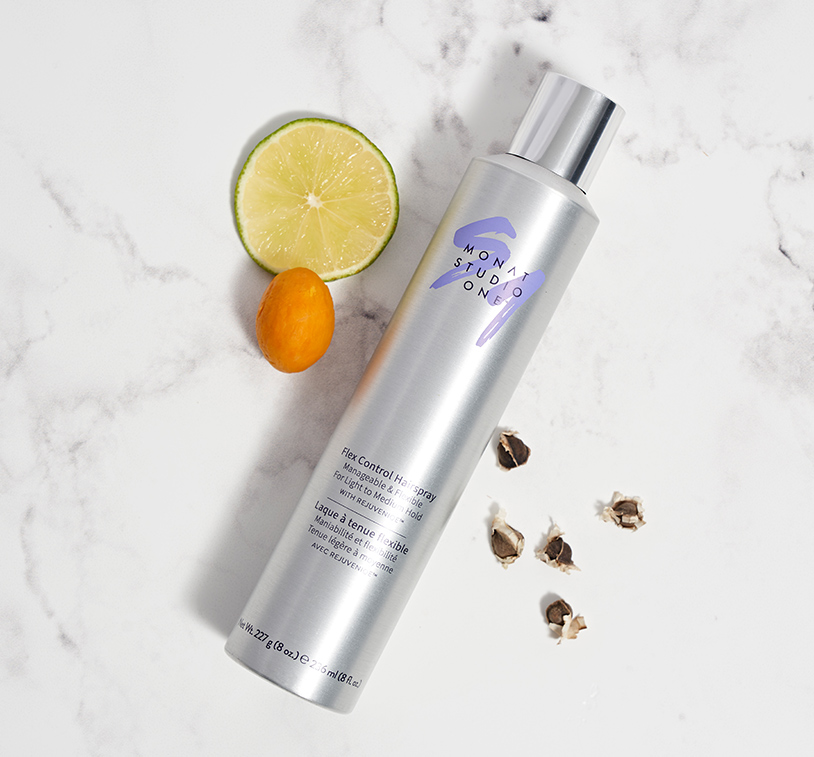 MONAT STUDIO ONE™ Flex Control Hairspray laying on a flat surface, next to different ingredients.