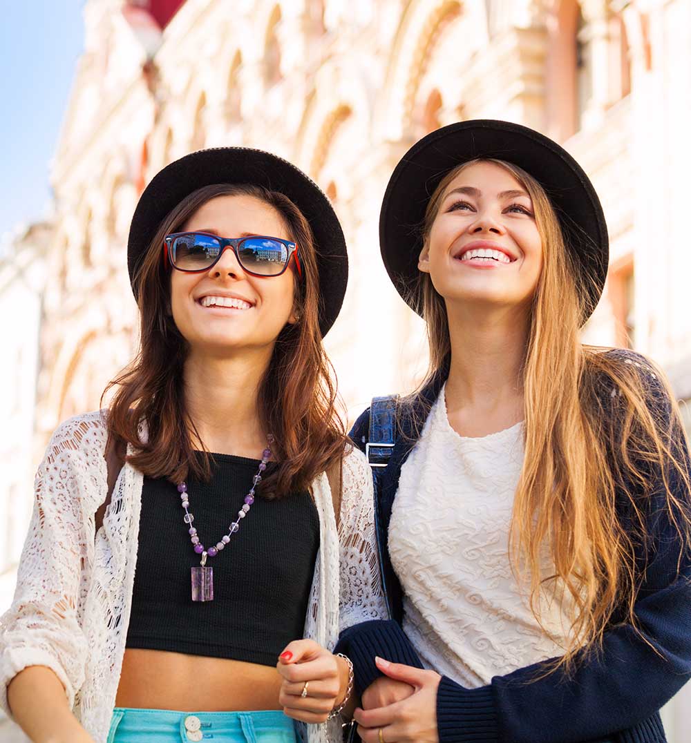 Young women walking together and admiring sightseeing attractions on the beautiful street during summer day time