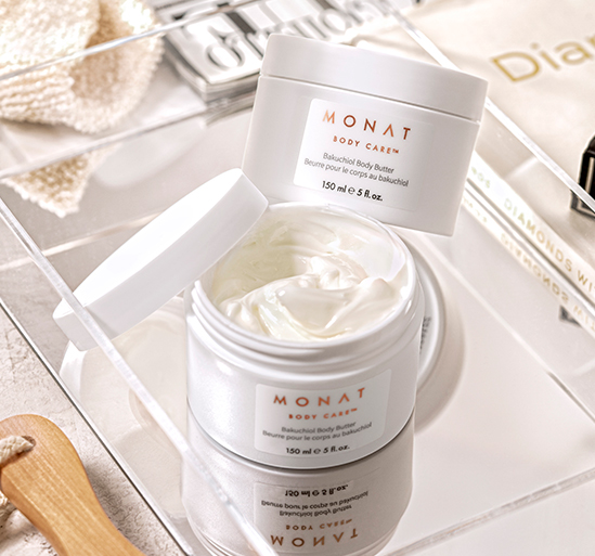 Two jars of MONAT BODY CARE™ Bakuchiol Body Butter over a mirror surrounded by magazines.