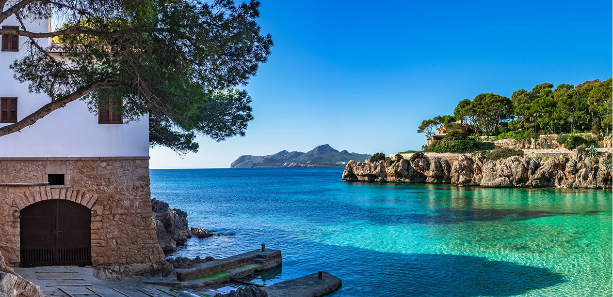 Crystal-clear turquoise waters along the coast of Mallorca with a traditional seaside house in Spain.