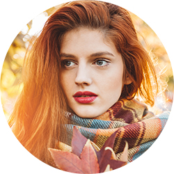 Portrait of young woman in autumn park. Holding leaves and enjoying in sunny autumn weather. Wearing warm clothing.