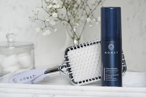 Monat Unknot Detangler displayed on a white marble counter along side a Monet squared hair brush.