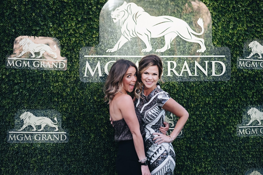Two women posing for a picture with MGM grand hotel casino logo as background