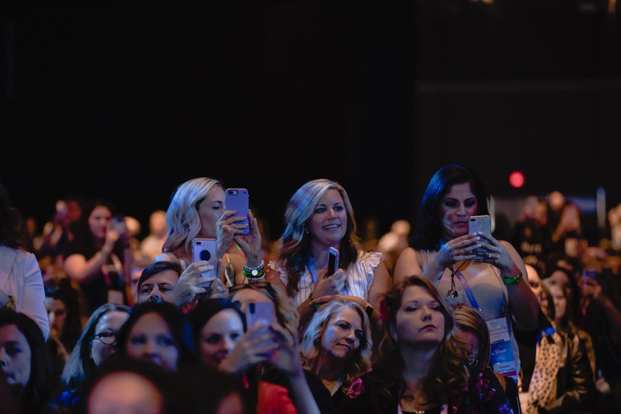 Group of people looking at the stage, and taking pictures with their phones
