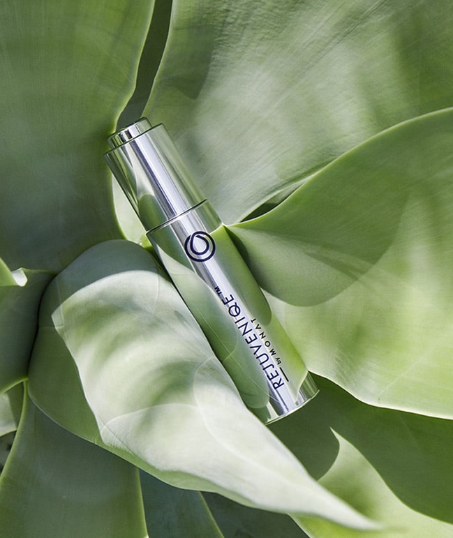 Image of a bottle of Rejuveniqe resting on the leaves