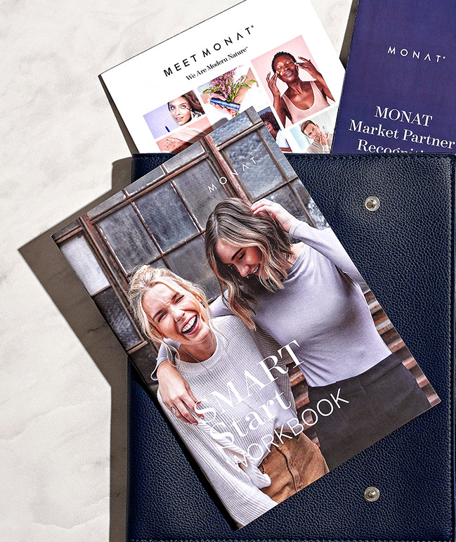 Picture of two women sitting down having coffee holding MONAT Smart Start Workbook.