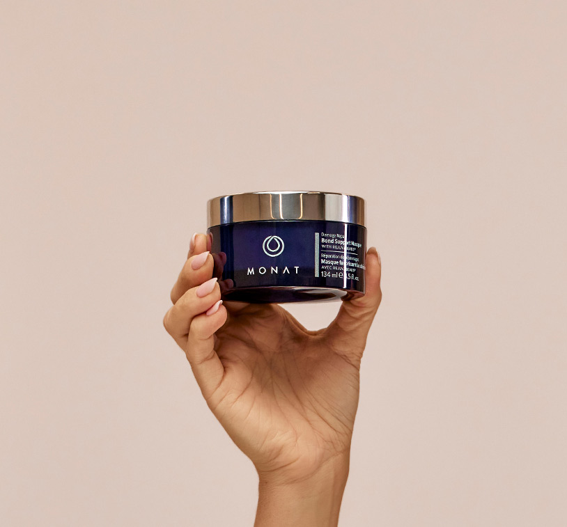 MONAT's Damage Repair Bond Support Masque being upheld by a woman's hand, showcasing 
   the product's aesthetics.