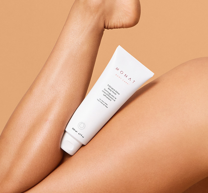 MONAT's Exfoliate & Refine Body Polish being gripped between a woman's thigh and calf. It's intended to demonstrate its 
      exceptional results after application.