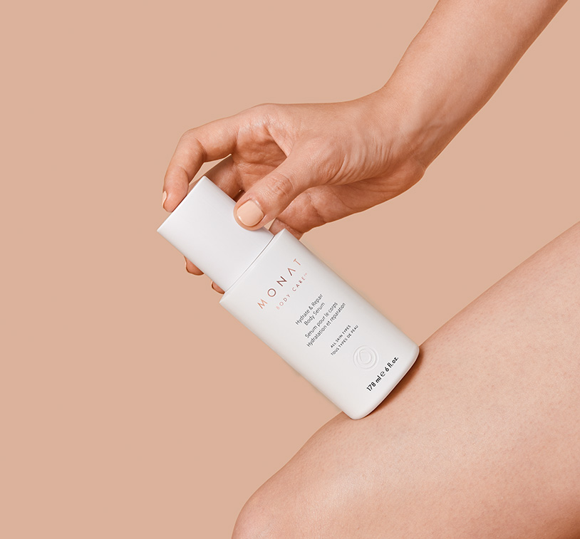 MONAT’s Hydrate & Repair Body Serum being held by a woman's hand against her leg. It's intended to show 
   exceptional results after treatment.