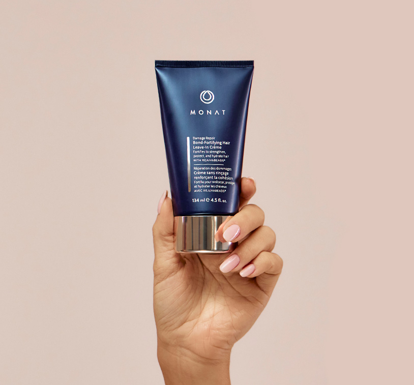 MONAT’s ® Damage Repair Bond-Fortifying Hair Leave-In Crème being upheld by a woman’s hand, showcasing the 
   product’s aesthetics.