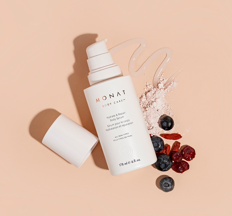 MONAT’s Hydrate & Repair Body Serum lays centered over a solid peach color background exhibiting its main ingredients 
         ornamenting the main product.