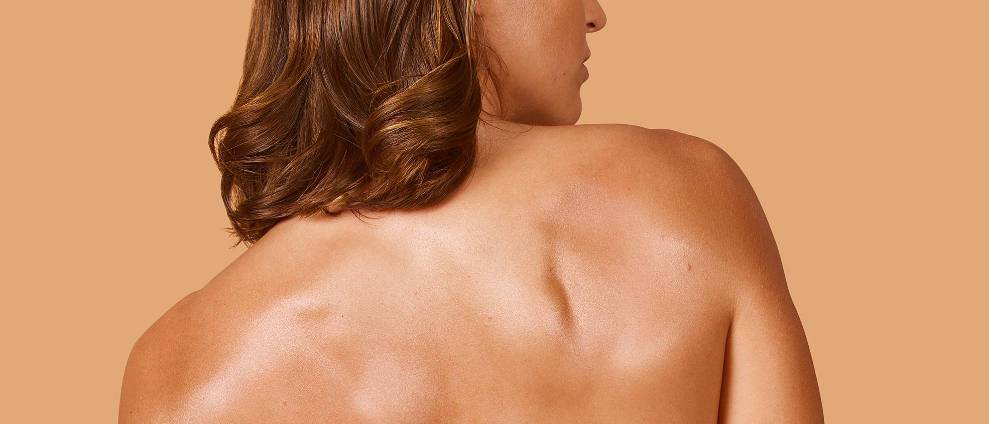 Back shot of a brunette woman looking to her right. It shows the radiance and smoothness this treatment provides to the skin after 
      application. 