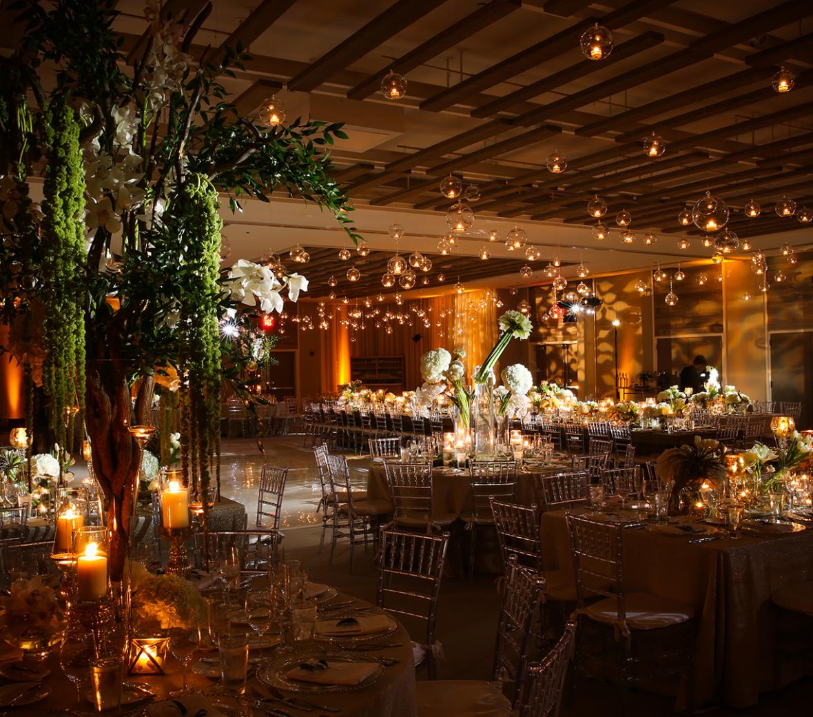 A luxury venue in a hotel with tables  decorated with floral arrangements and candles.
