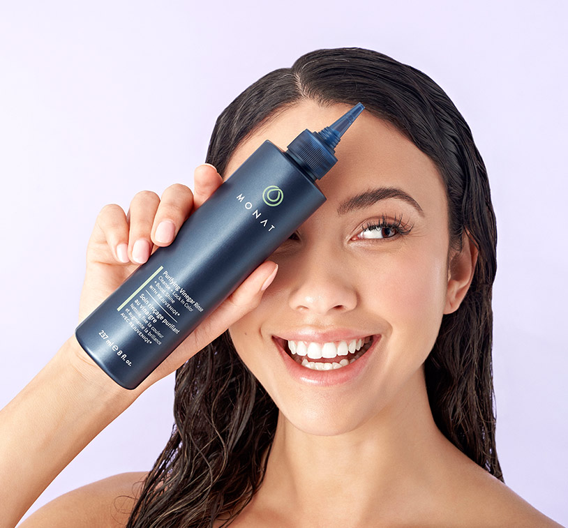 A brunette woman with wet hair smiling and holding Purifying Vinegar Rinse, overlayed 
      on an image with different ingredients that are in Purifying Vinegar Rinse.