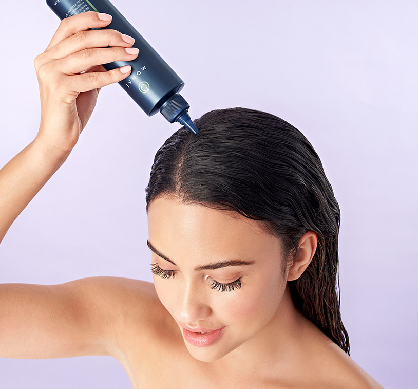 Woman with brunette hair applying Purifying Vinegar Rinse to the top of their wet hair