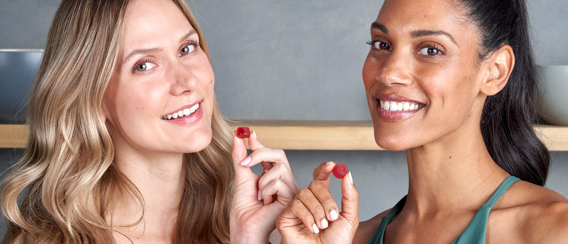 Blonde woman and brunette woman 
      each holding an Apple Cider Vinegar Gummie. 