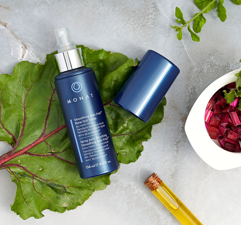 Smoothing Anti-Frizz™ Blow Out Spray laying on piece of lettuce, next to different ingredients.