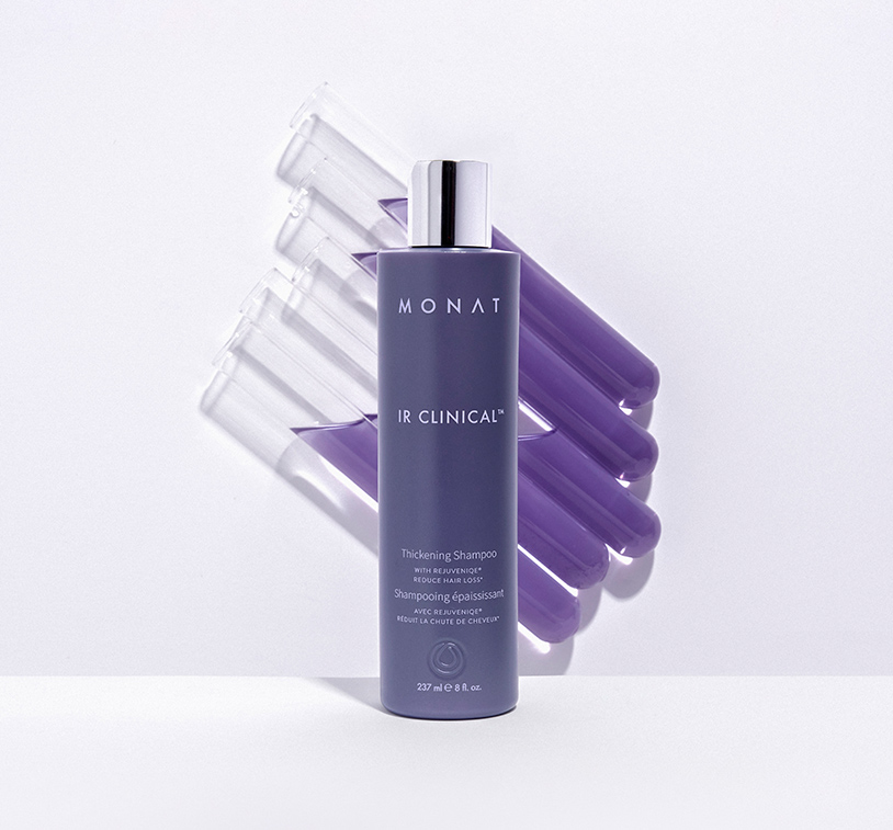 „IR Clinical™“ Thickening Shampoo on a white surface, infront of test tubes filled with purple liquid.