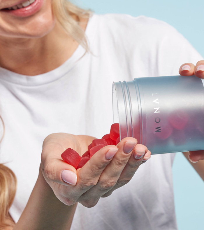 A blonde female pouring MONAT Apple Cider Vinegar Gummies to the palm of her hand.