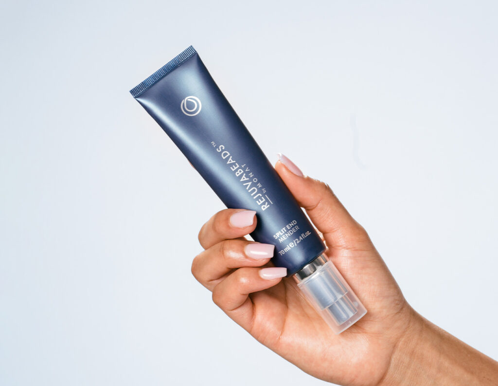 Hand holding REJUVABEADS™ by MONAT, our Lightweight leave-in serum
