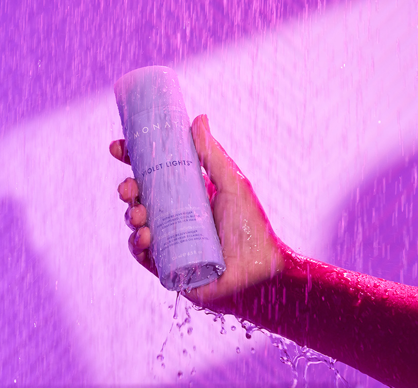 A hand holding Violet Lights™ Anti-Brass Shampoo in the shower.