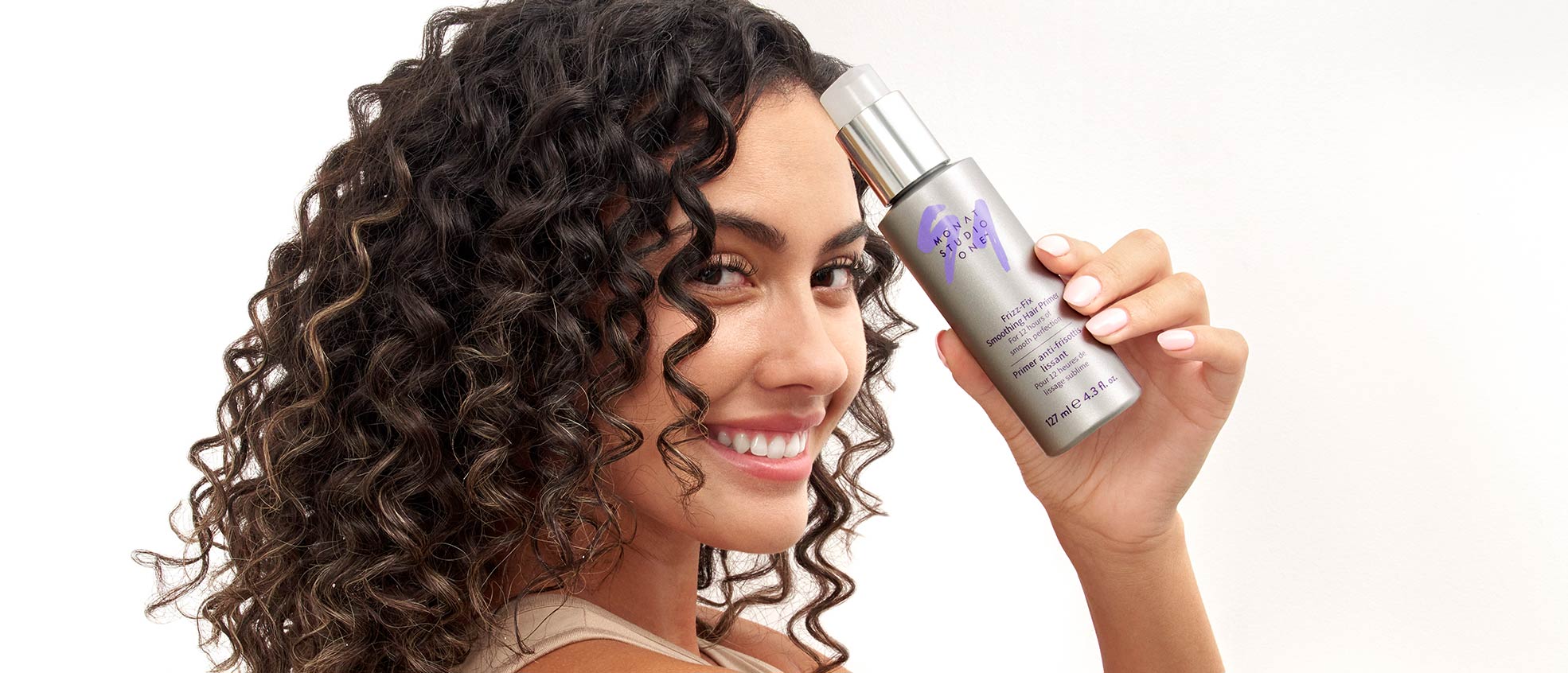curly hair female holding a Monat studio one product in front her face