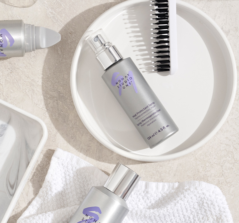 Heat protectant spray placed on a round plate surrounded by other Monat studio one products