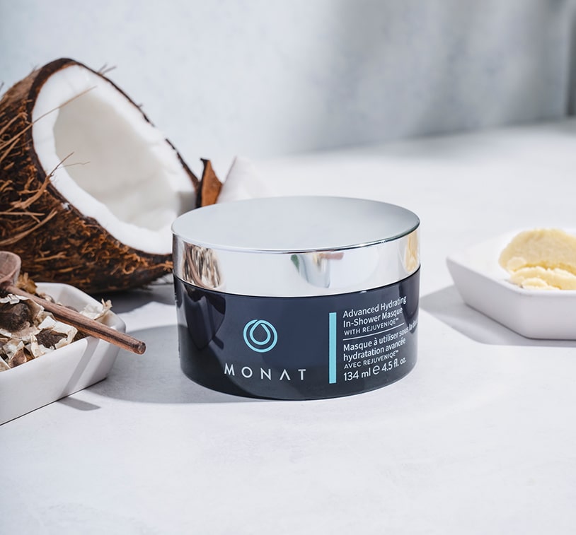 Advanced Hydrating In-Shower Masque on a white surface, next to coconut pieces.