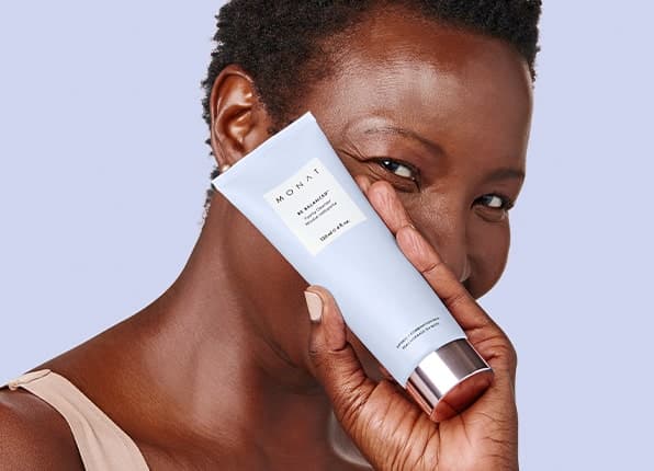 A female holding the BE BALANCED™ Foamy Cleanser infront of her face.