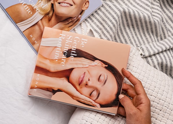A hand holding MONAT Skincare booklets. 