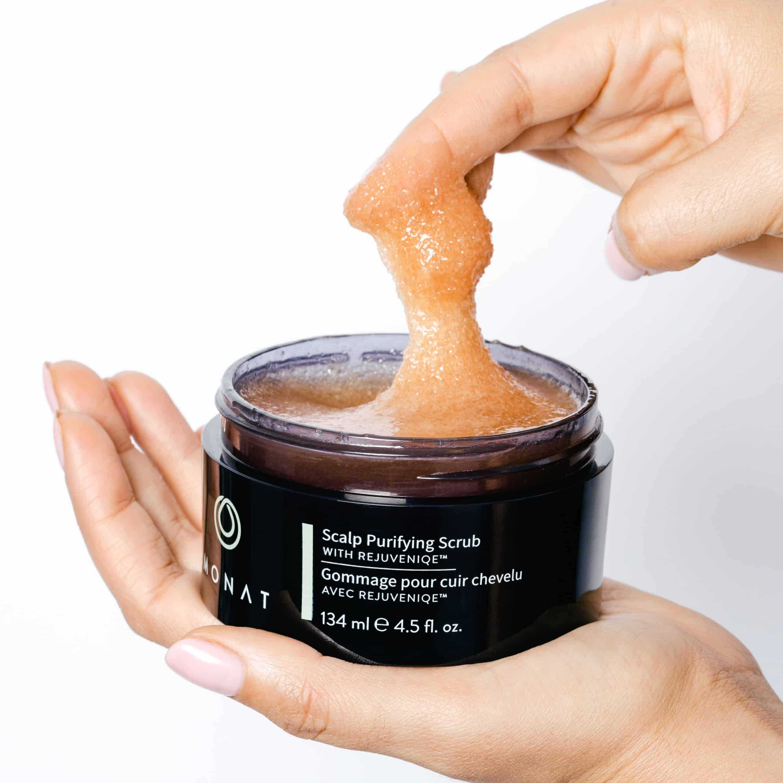 Woman's hands taking the recommended amount of Scalp Purifying Scrub out of its container.