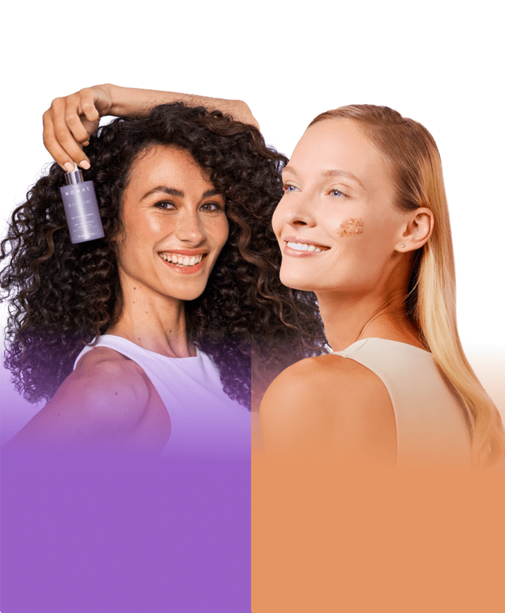 A brunnete curly famele smiling and holding a MONAT IR CLINICAL thining serum and a blond female smiling with a scrub smeared in her cheek