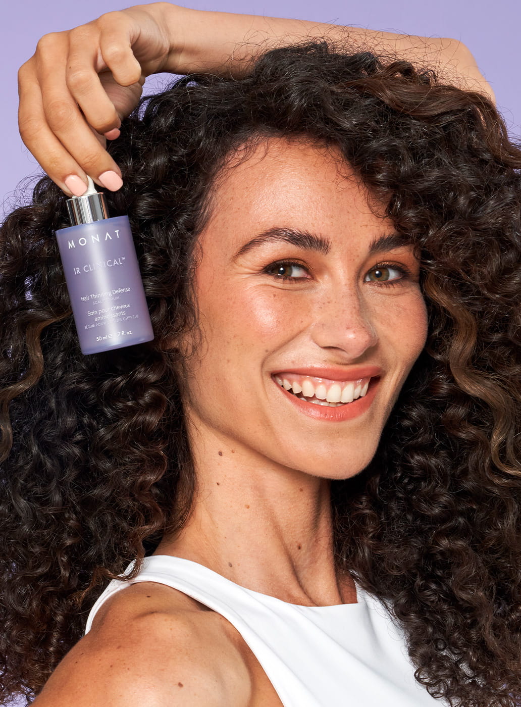 curly hair female posing with a IR CLINICAL™ HAIR THINNING DEFENSE next to her face