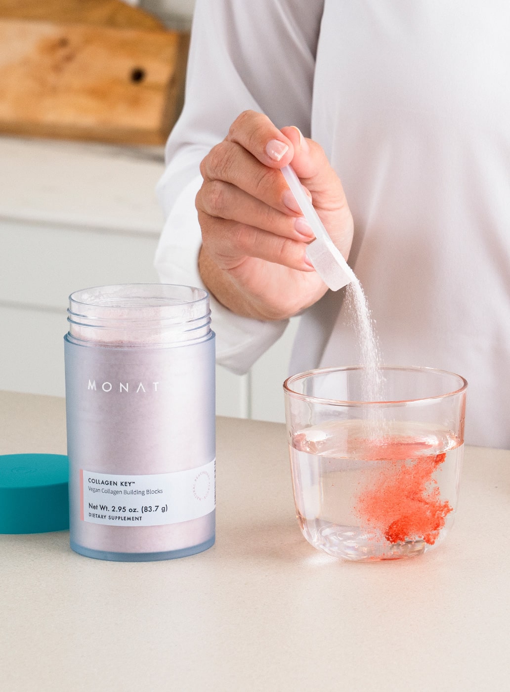 A woman stirring a drink of MONAT COLLAGEN KEY with a spoon