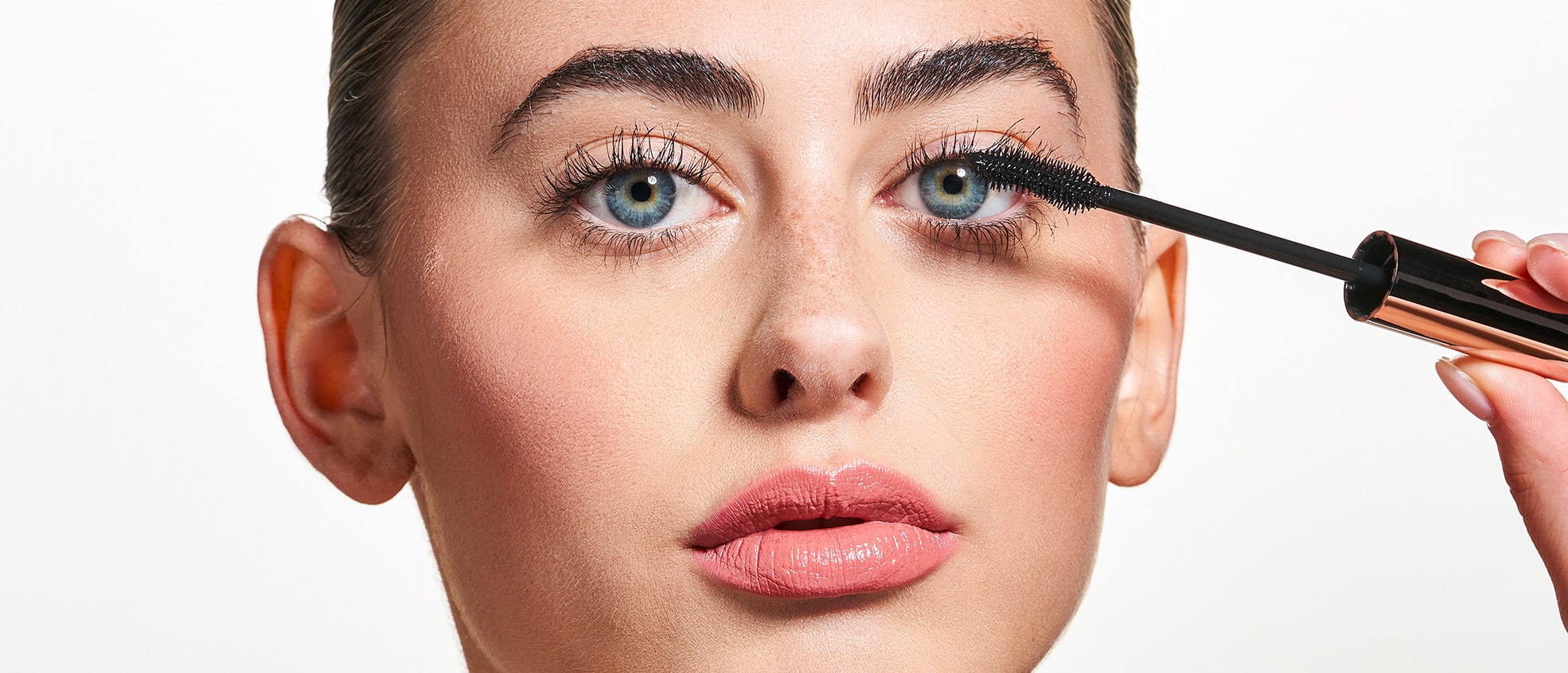 Female holding the MONAT IR™ Mascara Jetsetter Black brush and applying it to her lashes.