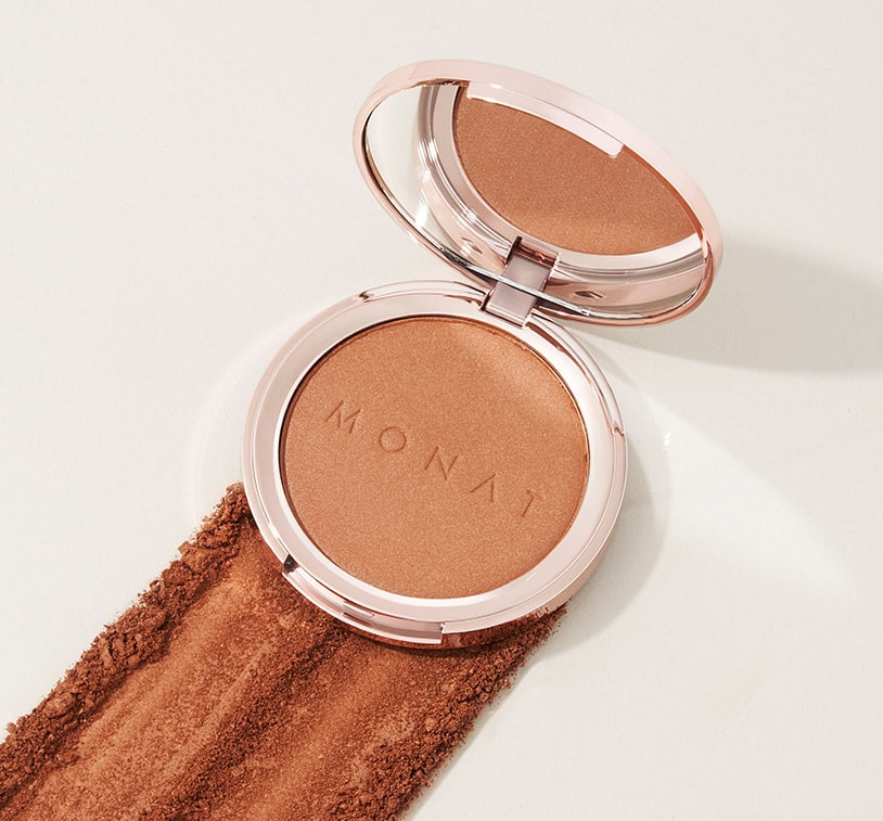 An open MONAT Radiant Bronzer™ on top of golden bronzer powder.