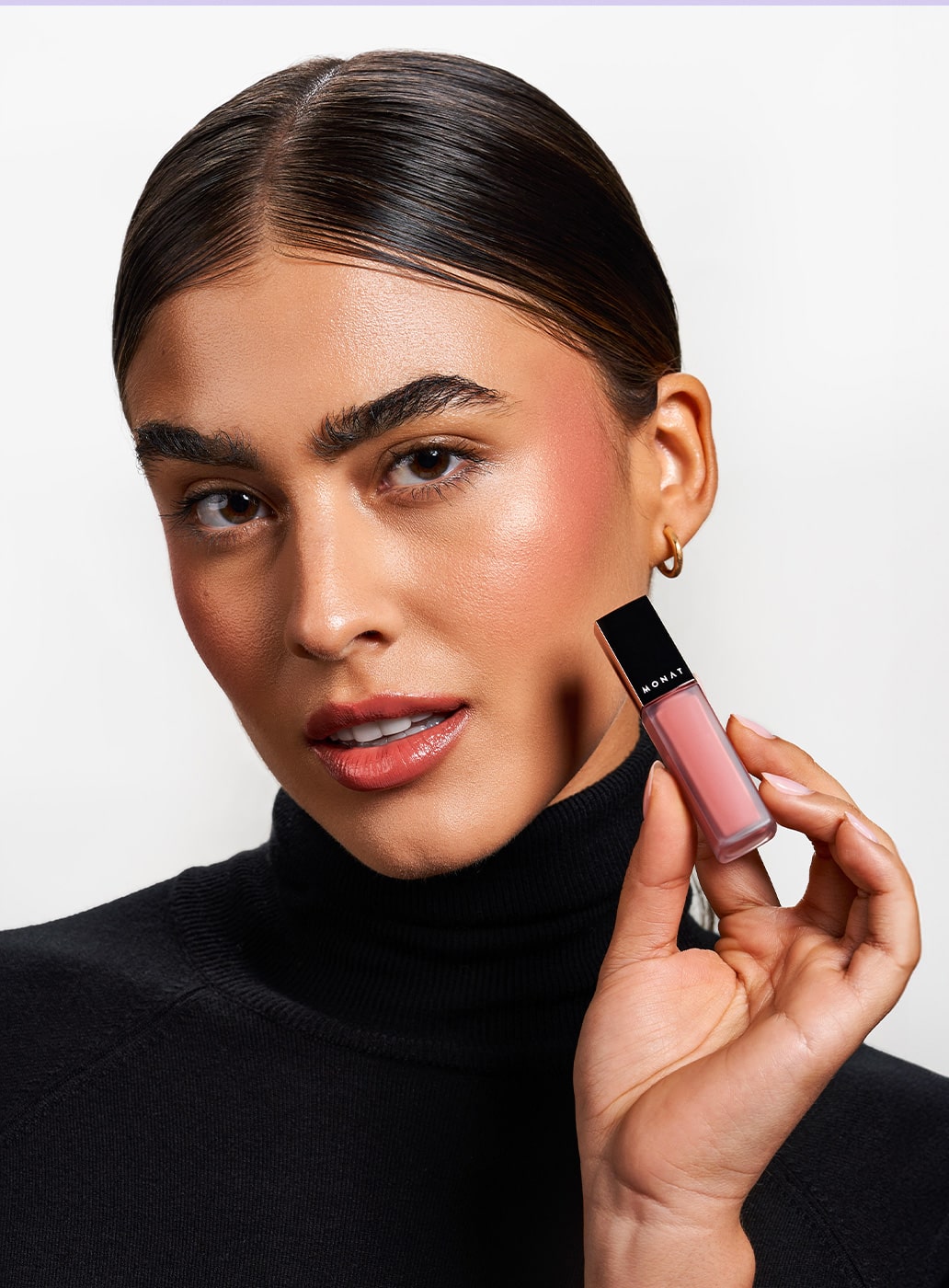 Female holding the MONAT Liquid Lipstick™ in shade Posh and wearing the lipstick