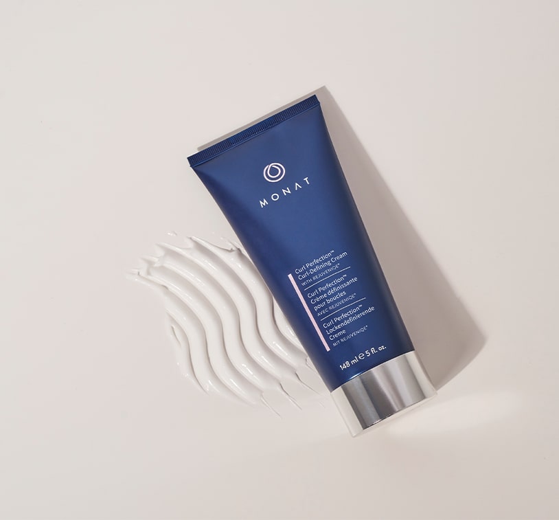 Tube of MONAT Curl Perfection™ Curl Defining Cream with a sample texturized product  placed on a white background. 