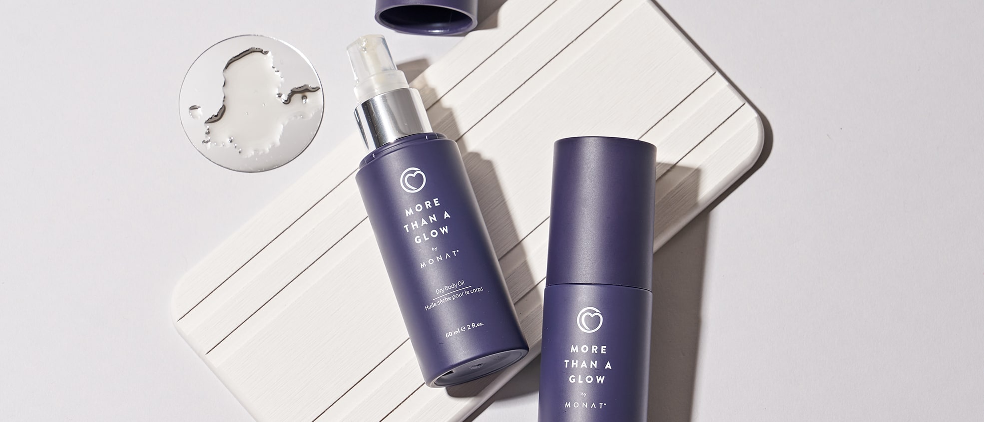 Image showing two bottles of 'More Than a Glow by MONAT' product arranged against a purple background with one of the bottles having their caps off.