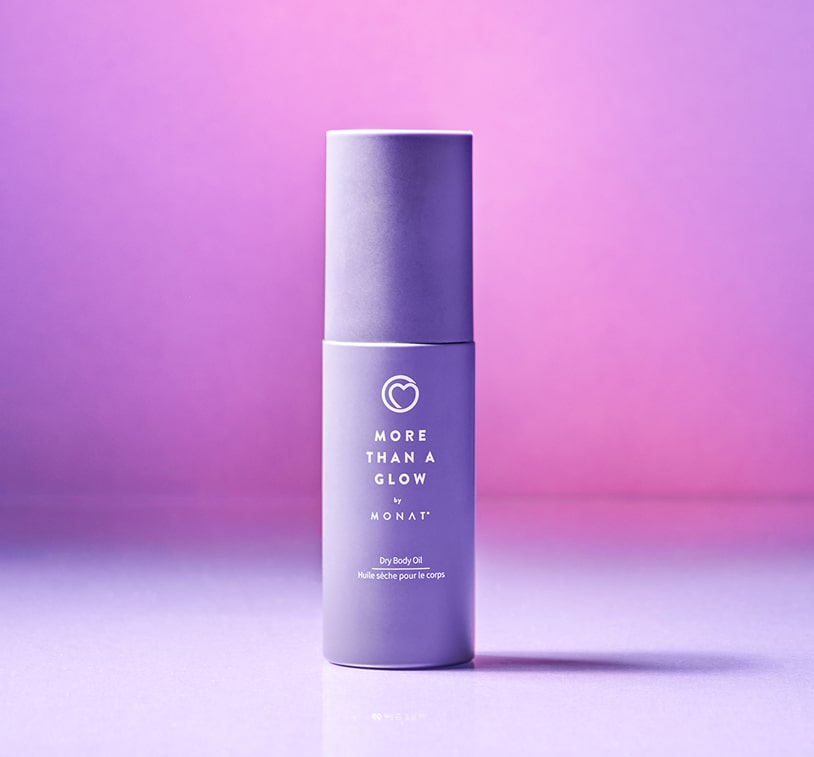 Image of a woman with curly hair holding a bottle of 'More Than a Glow by MONAT' product against a purple and pink background.