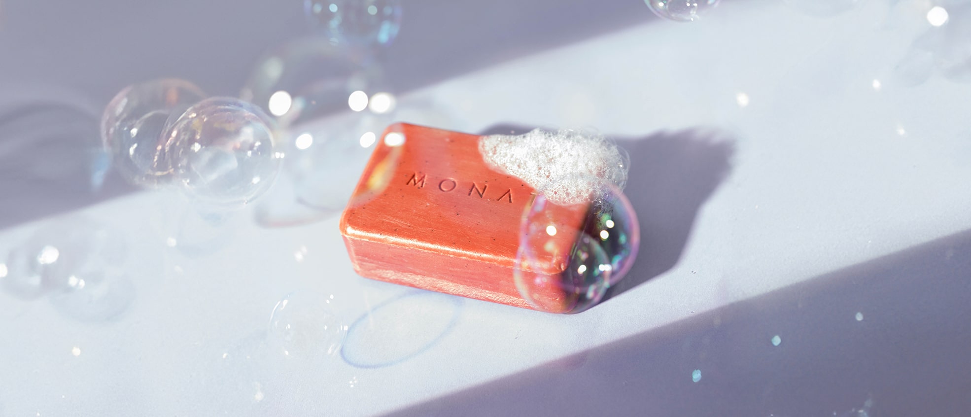 MONAT body bar with bubbles on it, resting on a wet surface.